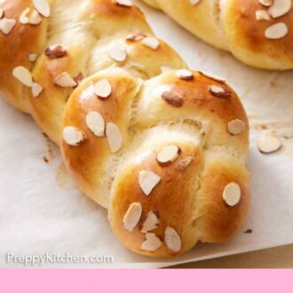 Pinterest graphic of a close view of a loaf of two loaves of tsoureki on a lined sheet pan.