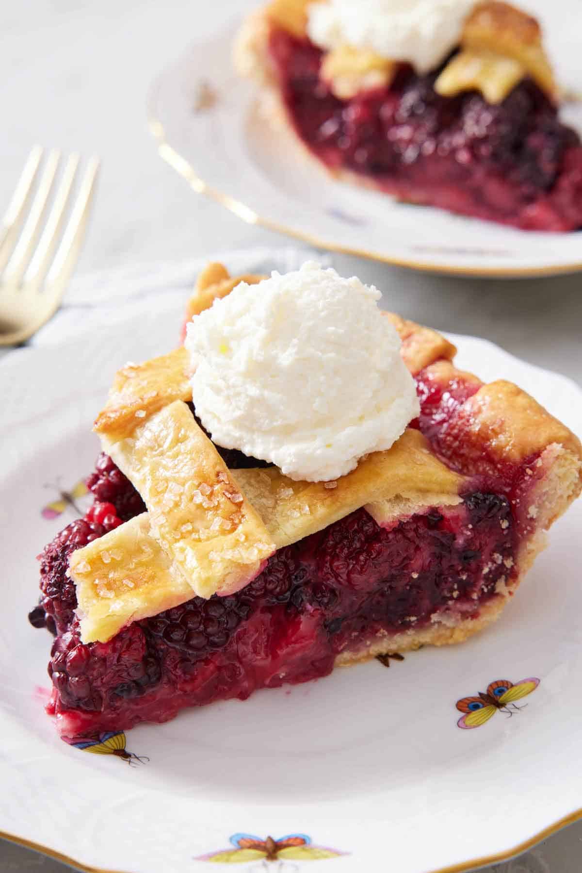 A plate with a slice of blackberry pie with a scoop of ice cream on top.