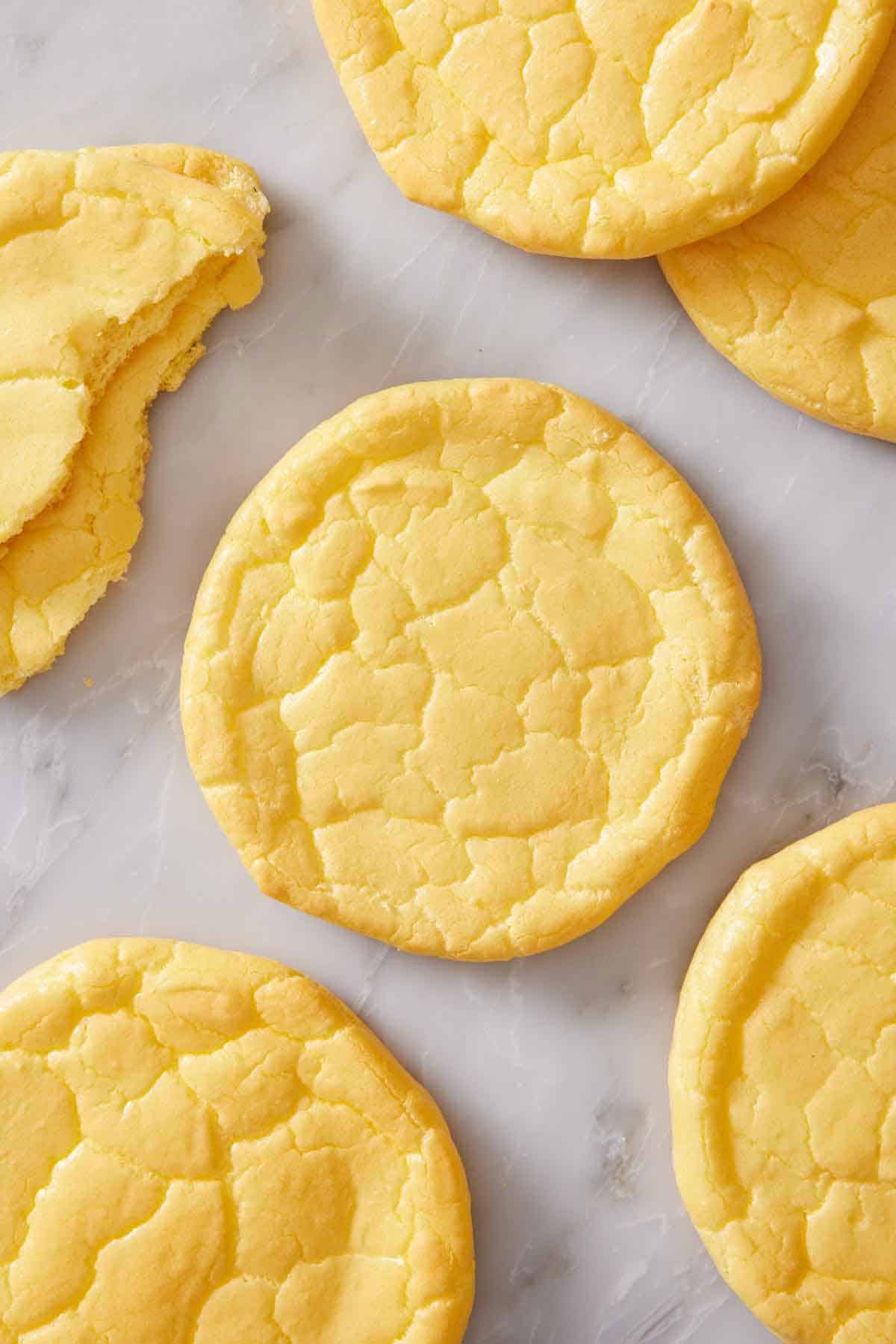 Overhead view of cloud bread on a marble counter. One on the side torn in half.