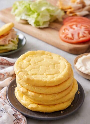 A plate with a stack of five cloud bread with sandwich fillings in the background.