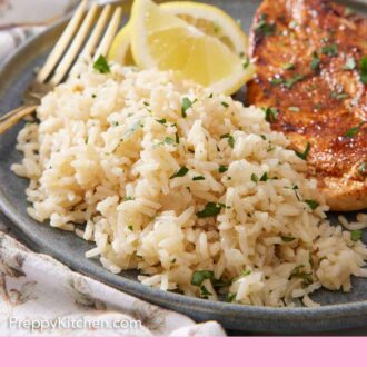 Pinterest graphic of a plate with rice pilaf with lemon wedges and meat.