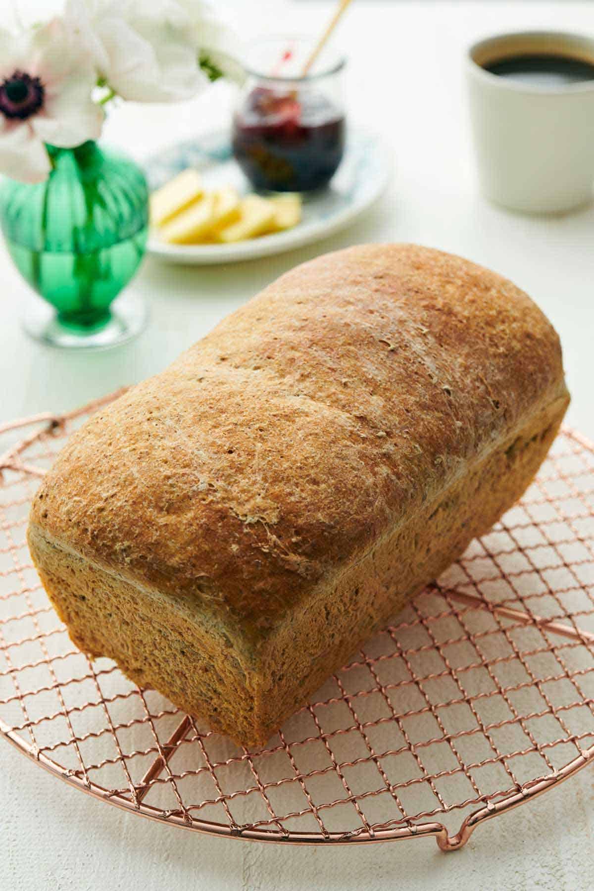 A loaf of rye bread on a wire cooling rack.