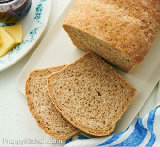 Pinterest graphic of a top down view of a loaf of rye bread with two slices cut. Jam and butter off to the side.