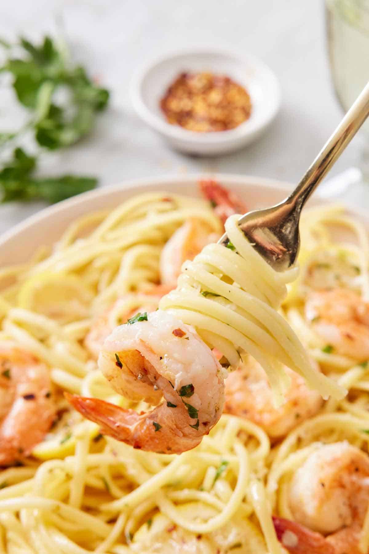 A forkful of shrimp linguine lifted with noodles wrapped around the fork.