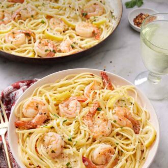 Pinterest graphic of shrimp linguine on a plate with a glass of wine and skillet with more shrimp linguine in the back.