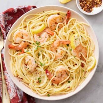 Overhead view of a plate of shrimp linguine with a linen napkin and fork on the side.