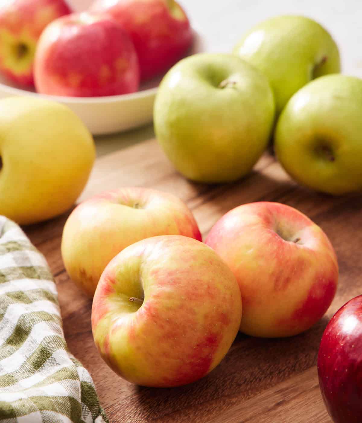 Multiple apples on a cutting board.