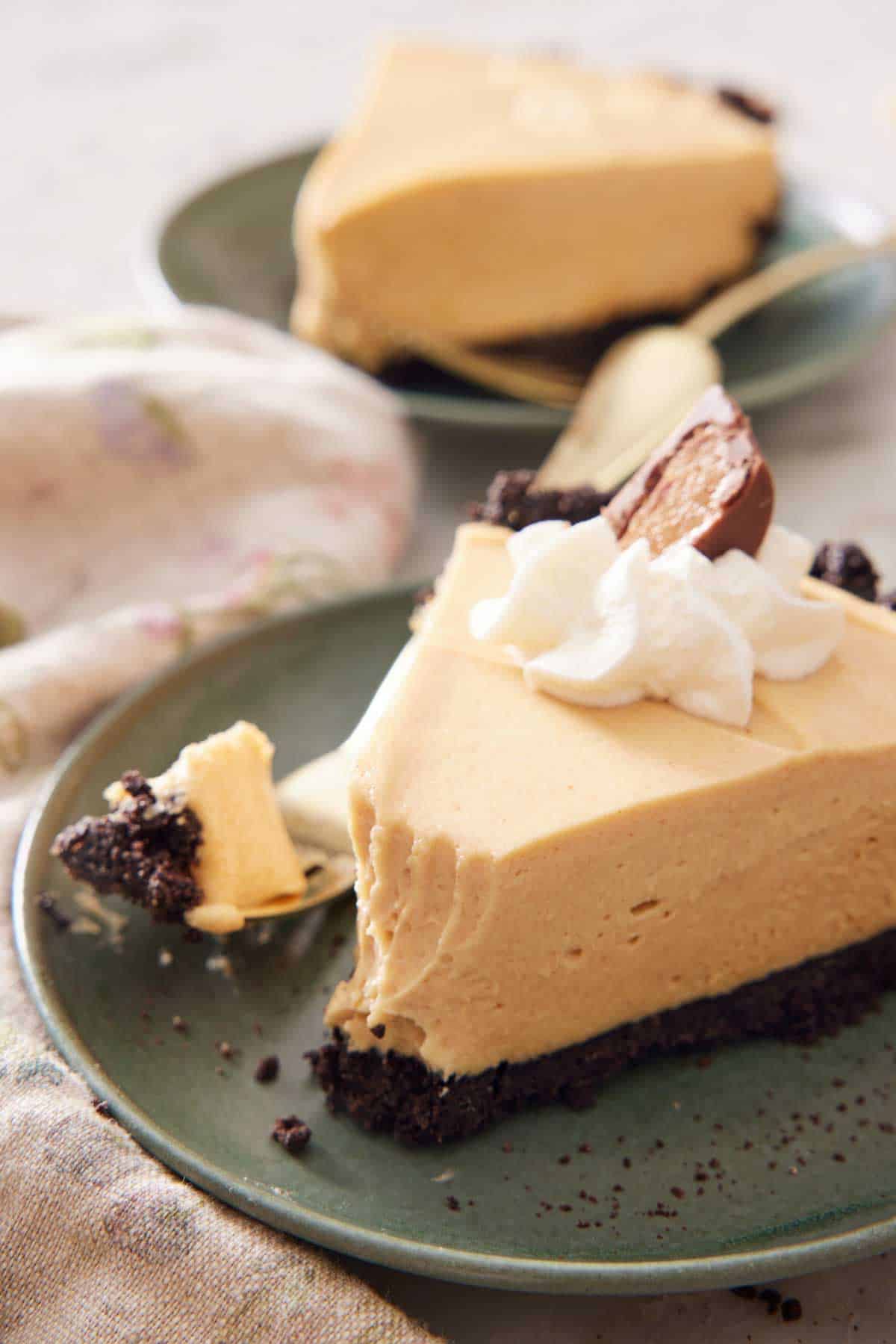 A slice of peanut butter pie on a plate with the tip of the slice on a fork beside it. A second slice in the background.