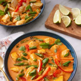 Pinterest graphic of two bowls of Thai red curry with a wooden board with lime wedges in between.