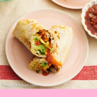 Pinterest graphic of a pink plate with a breakfast burrito, cut in half, with one half leaned on top of the other.