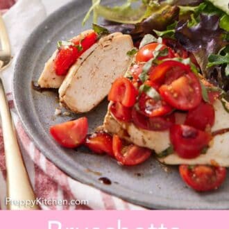 Pinterest graphic of a plate with a bruschetta chicken breast with two bites cut with some mixed greens on the side.