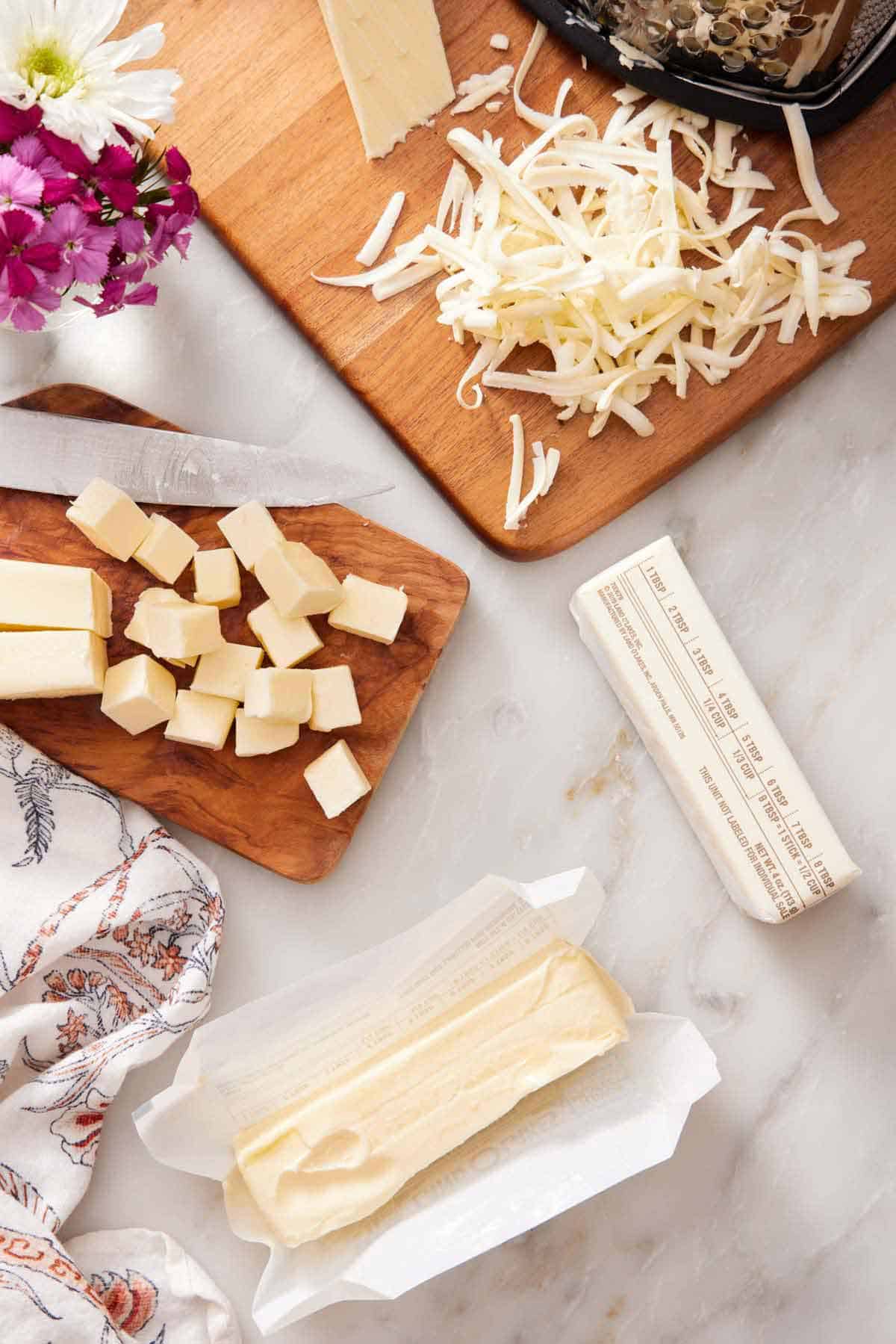Overhead view of softened butter in three forms: a stick, cut into cubes, and shredded.