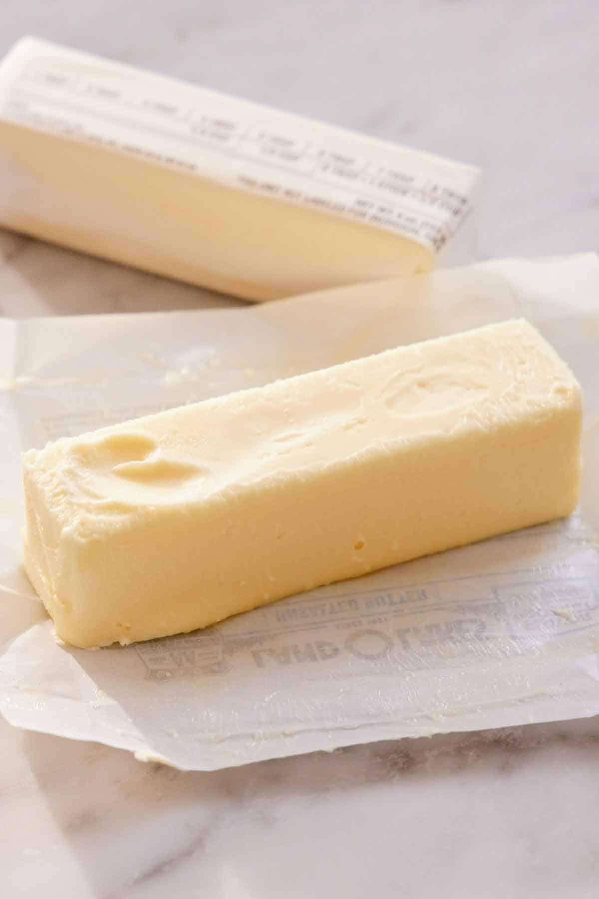 A stick of softened butter in an opened wrapper. A second stick of butter in the background.