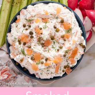 Pinterest graphic of a bowl of smoked salmon dip topped with fresh dill and capers with sliced cucumbers, radishes, and bread on the side.