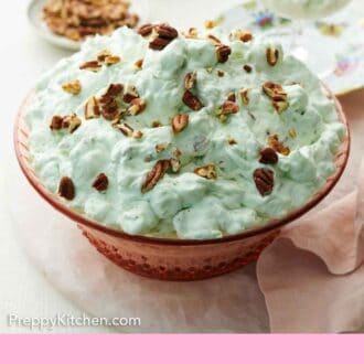 Pinterest graphic of a serving bowl of Watergate salad topped with chopped pecans.