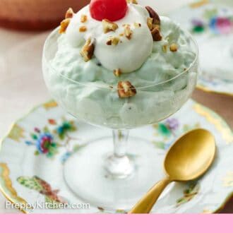 Pinterest graphic of a dessert bowl with Watergate salad topped with whipped cream, pecans, and a maraschino cherry.