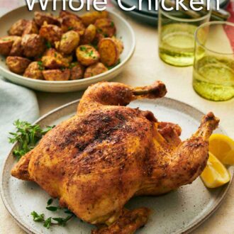 Pinterest graphic of a platter with air fryer whole chicken with some herbs and lemon wedges. Two glasses of water and baby potatoes in the background along with plates and forks.