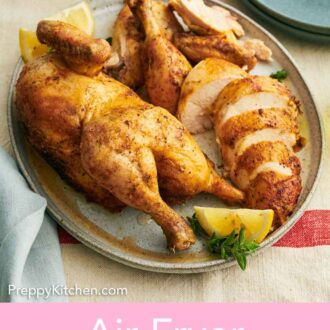 Pinterest graphic of a cut air fryer whole chicken on a platter with lemon wedges and parsley.