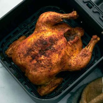 An overhead view of crispy air fryer whole chicken in the air fryer basket.