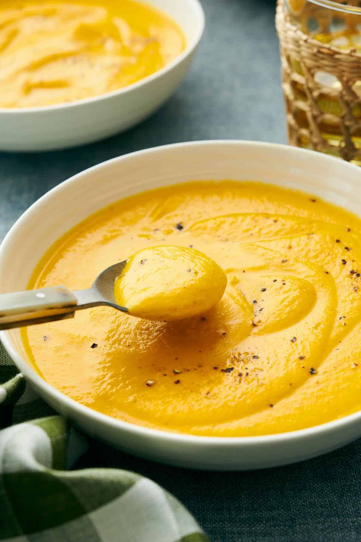 A spoonful of carrot soup lifted from a bowl.