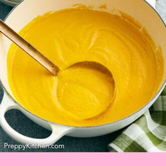 Pinterest graphic of a pot of creamy carrot soup with a ladle.