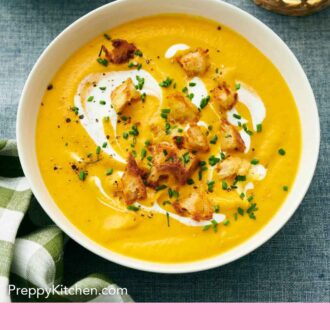 Pinterest graphic of carrot soup in a bowl topped with cream and croutons.