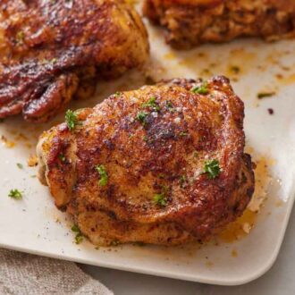 A close up view of Instant Pot chicken thigh on a platter with more in the background.