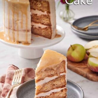Pinterest graphic of a slice of caramel apple cake on a plate with the rest of the cake in the background on a white cake stand.