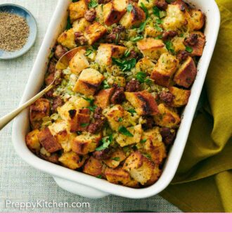 Pinterest graphic of a white baking dish of sausage stuffing with a spoon inside.