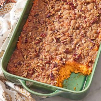 Overhead view of a green baking dish of sweet potato casserole with a serving scooped out.