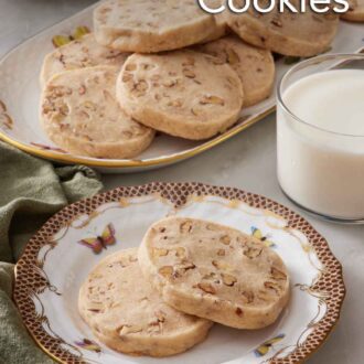 Pinterest graphic of a plate with two pecan shortbread cookies with a glass of milk and platter of more cookies in the background.
