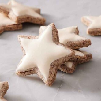 Multiple zimtsterne with a small stack in the middle with one cookie leaning on the stack.