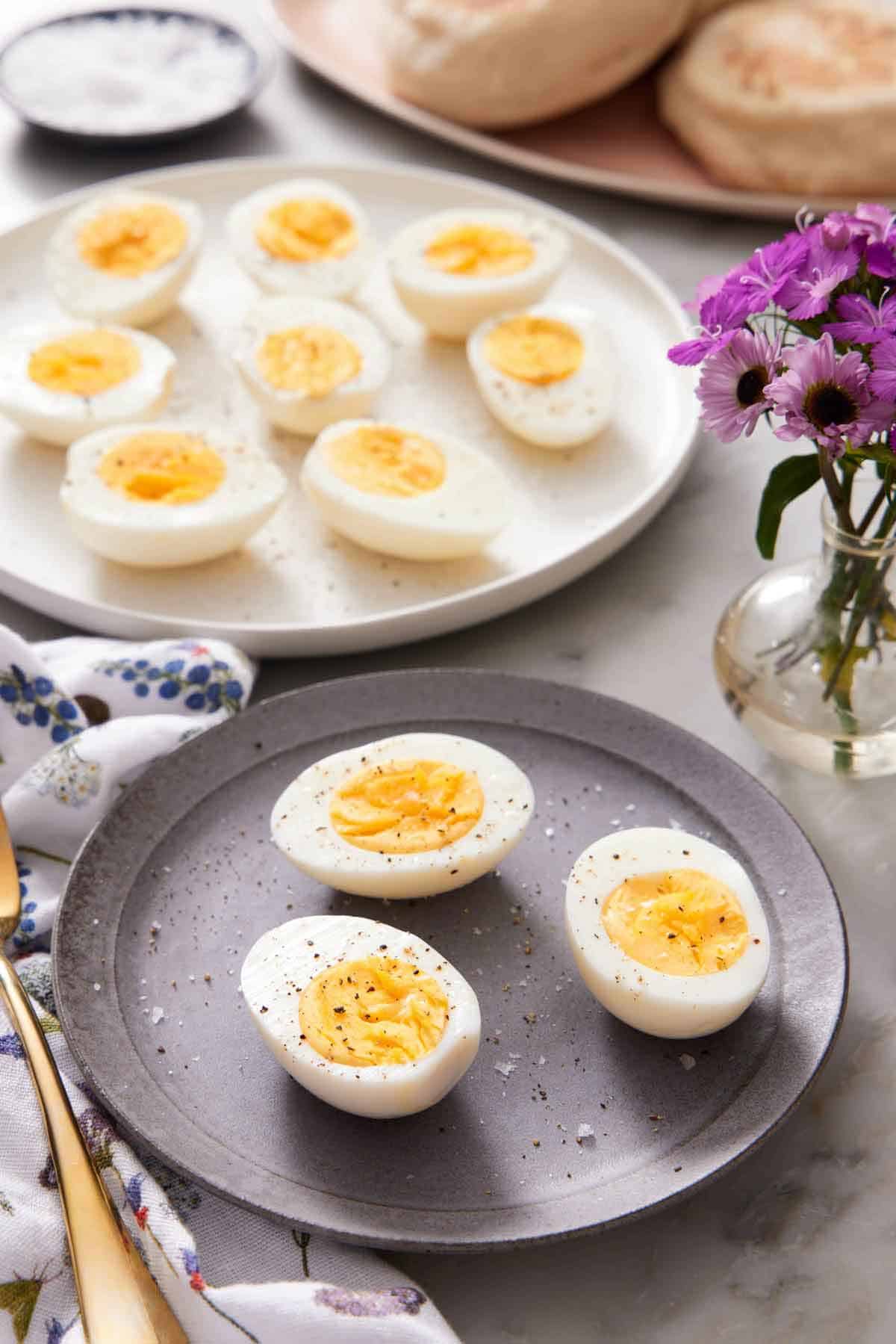 A plate with air fryer hard boiled eggs cut in half on a plate with a platter in the background with more eggs.