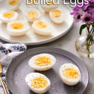 Pinterest graphic of a plate with air fryer hard boiled eggs cut in half on a plate with a platter in the background with more eggs.