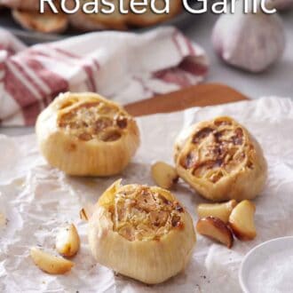 Pinterest graphic of three air fryer roasted garlic also with roasted cloves on a parchment-lined wooden serving board.