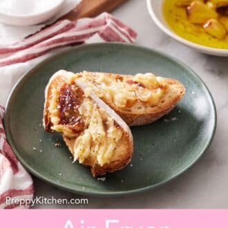 Pinterest graphic of a plate with two pieces of bread with air fryer roasted garlic spread on top.
