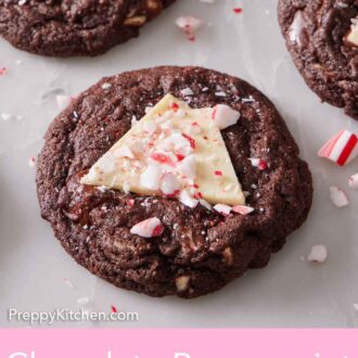 Pinterest graphic of an overhead view of chocolate peppermint bark cookie topped with crushed candy canes. More in the background.