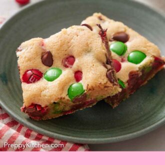 Pinterest graphic of a green plate with two pieces of M&M cookie bars.