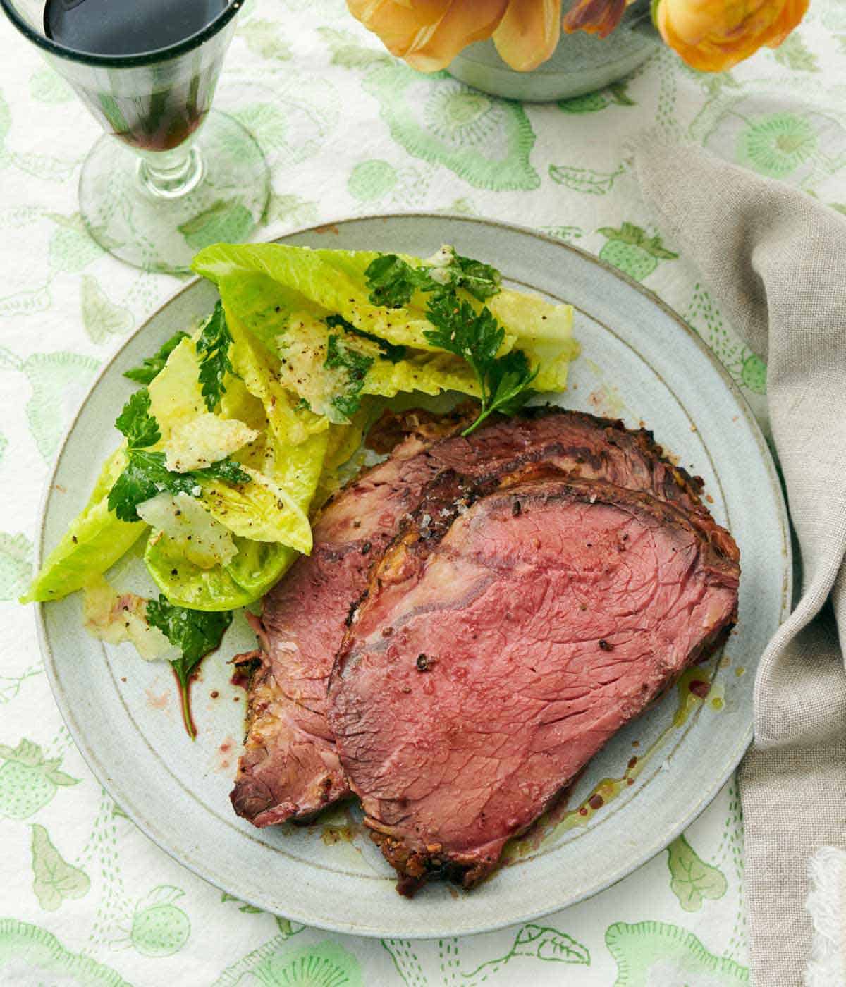 A plate with two slices of prime rib with a side salad.