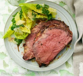 Pinterest graphic of two slices of prime rib on a plate with a side salad.