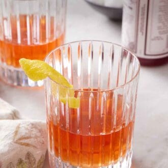 Pinterest graphic of two glasses of Sazerac with a lemon twist garnish on the rims of the glasses.