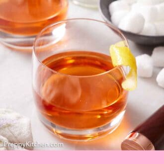 Pinterest graphic of two glasses of Sazerac with a lemon twist garnish.