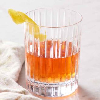 Sazerac in a glass with a lemon zest garnish on the rim.