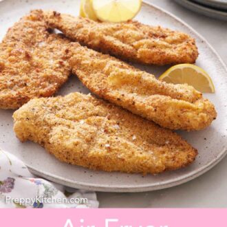 Pinterest graphic of a platter of air fryer chicken cutlets with cut lemon wedges.