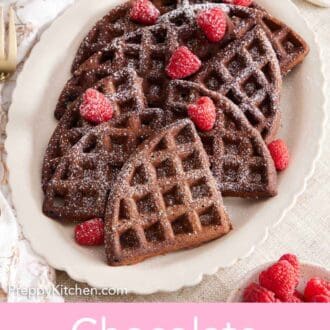 Pinterest graphic of an overhead view of a platter of chocolate waffles topped with powdered sugar and raspberries.