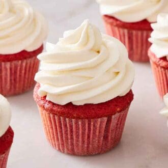 Multiple red velvet cupcakes with ermine frosting on top.