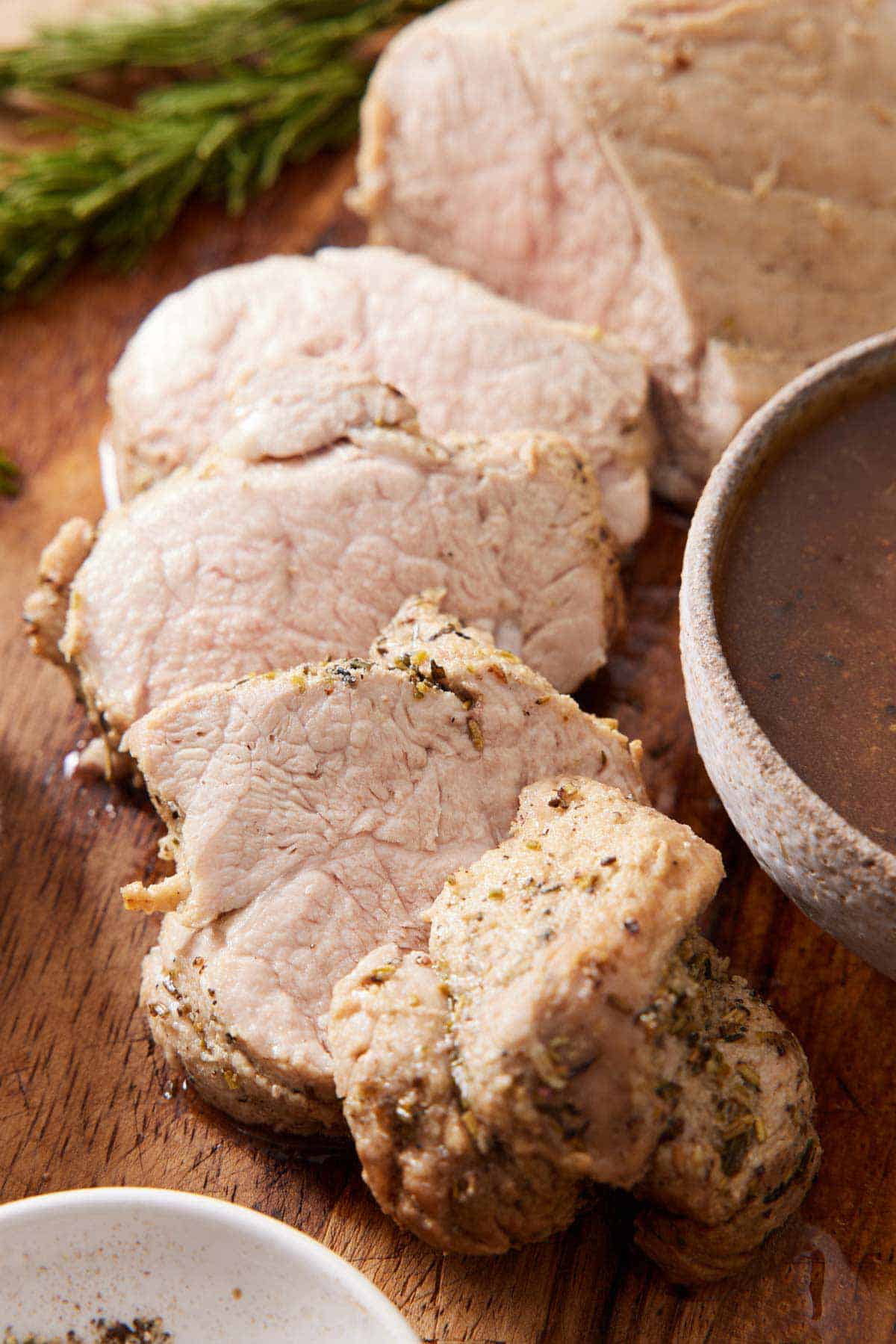 A close up view of sliced Instant Pot pork tenderloin on a wooden serving board.