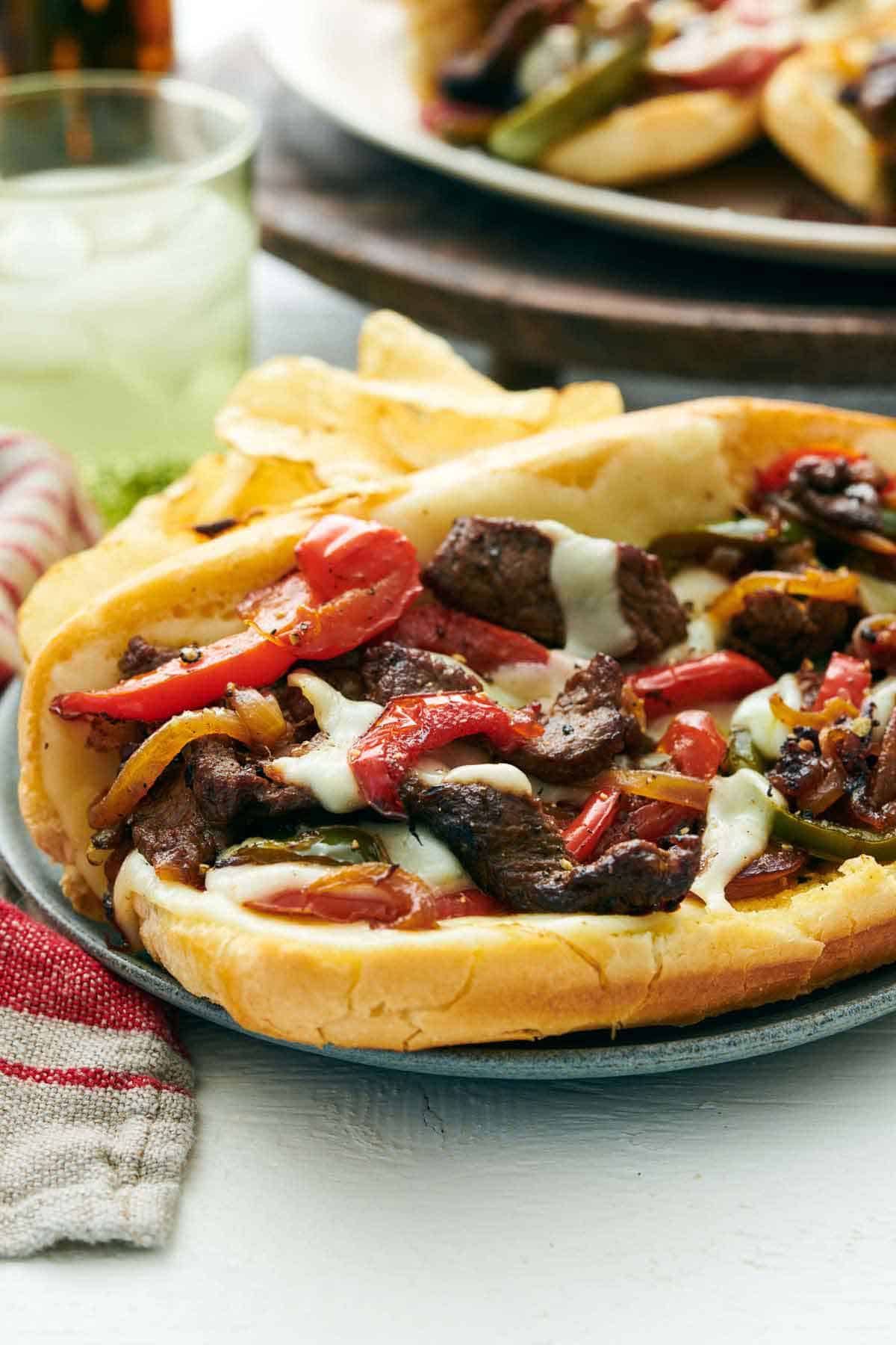A close up view of the filling of a Philly cheesesteak on a plate with chips.