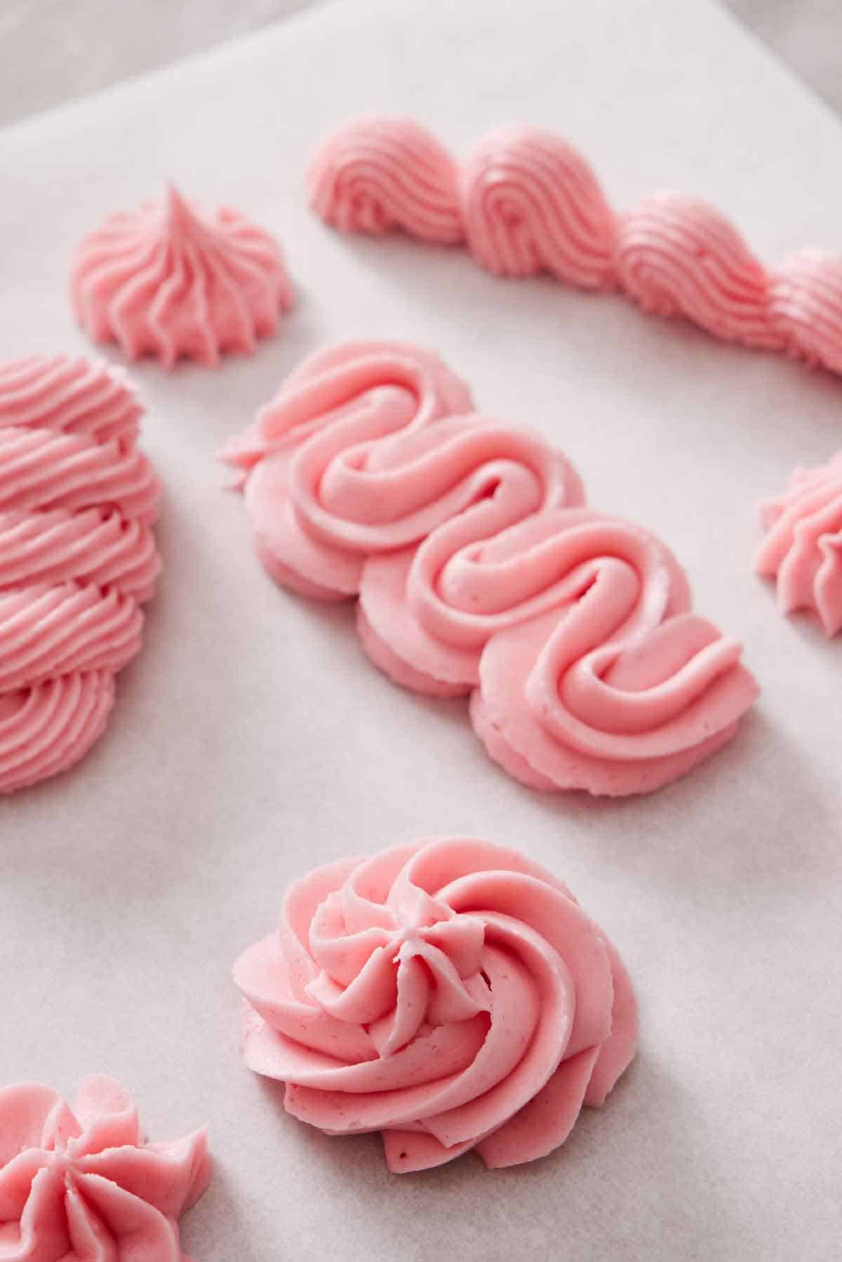 Parchment with raspberry buttercream piped in different styles.