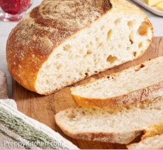 Pinterest graphic of a loaf of sourdough bread on a wooden cutting board with a few slices cut in front.